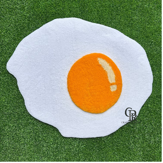 Fried egg shaped hand-tufted rug front view on green grass with white base and bright yellow yolk.