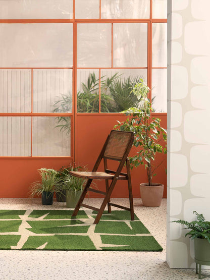 Moqui Green hand tufted wool rug styled in a natural interior setting highlighting geometric design and forest green tone.