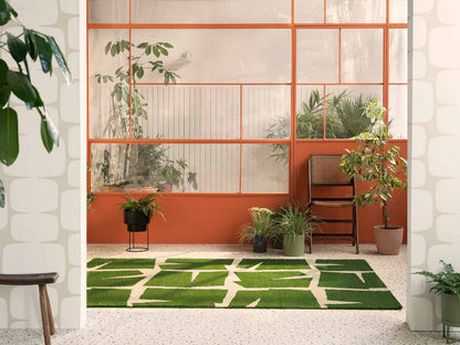 Moqui Green hand tufted wool rug styled in a bright interior featuring bold geometric pattern in green and ivory tones.