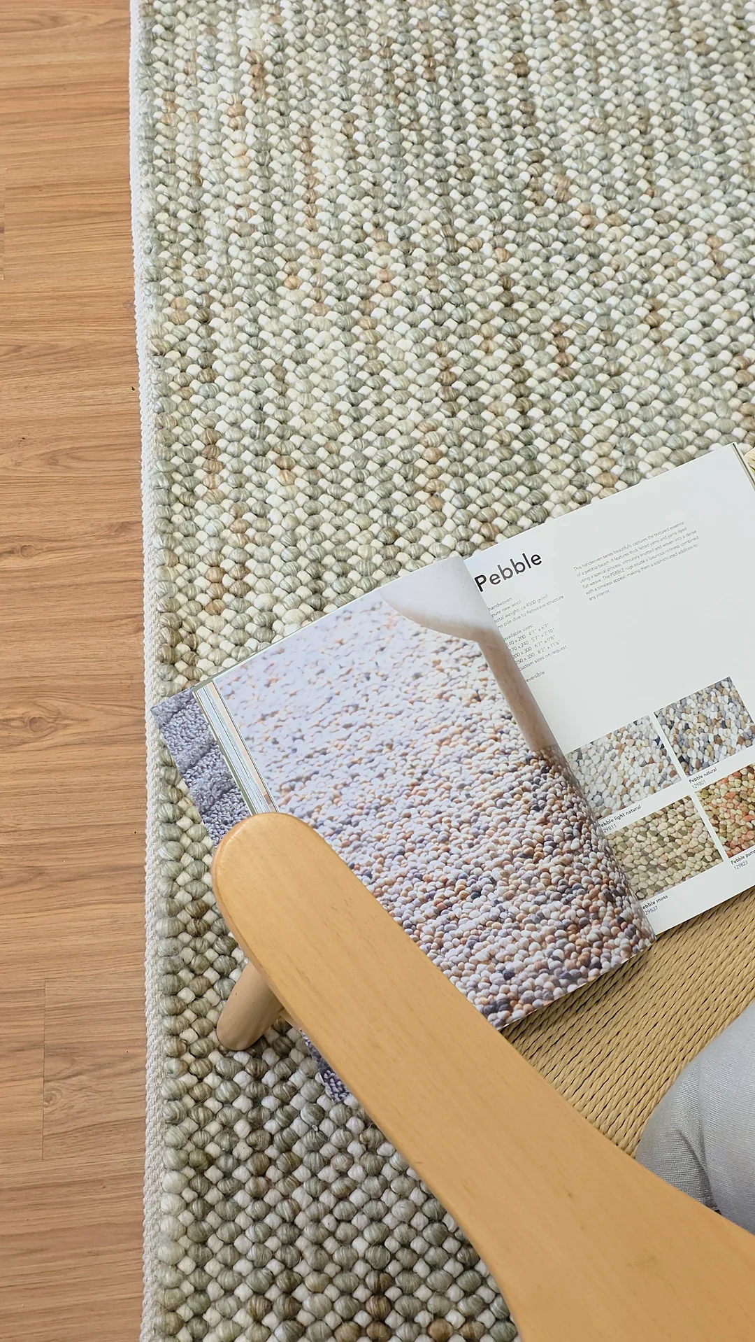 Pebbles Sage Green flatweave rug in lifestyle setup with wooden furniture on hardwood floor for modern living room.