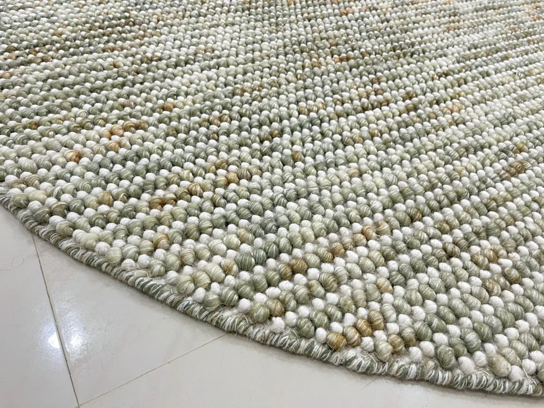Close-up of Pebbles Sage Green round flatweave rug texture showing detailed weave and natural sage green tones.
