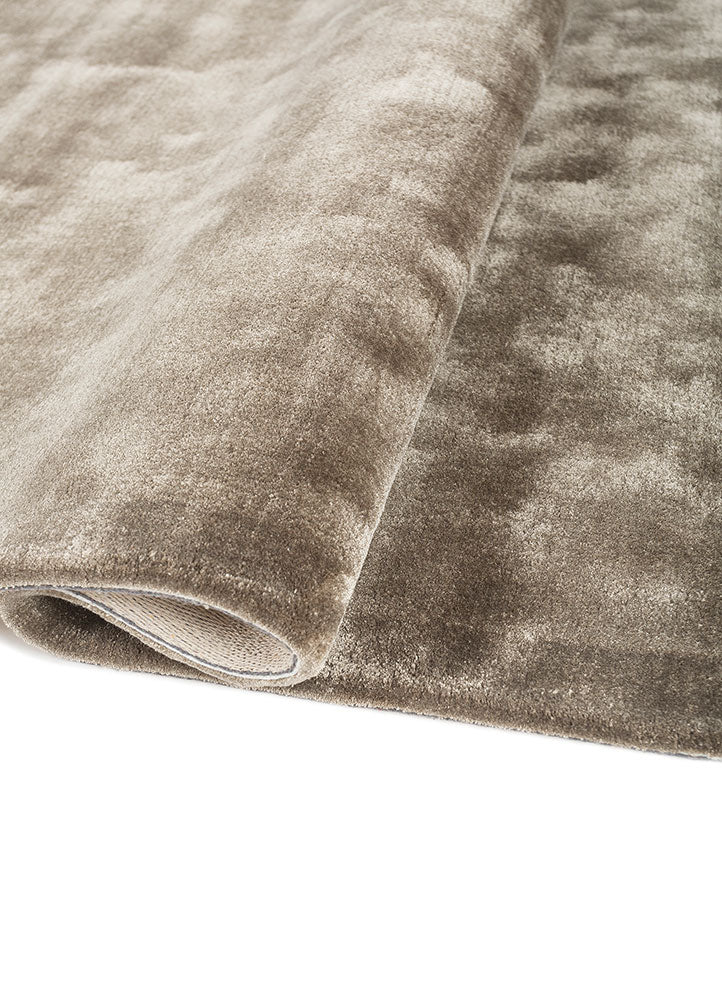 Folded view of hand tufted wool rug showing soft pile thickness and elegant taupe color.
