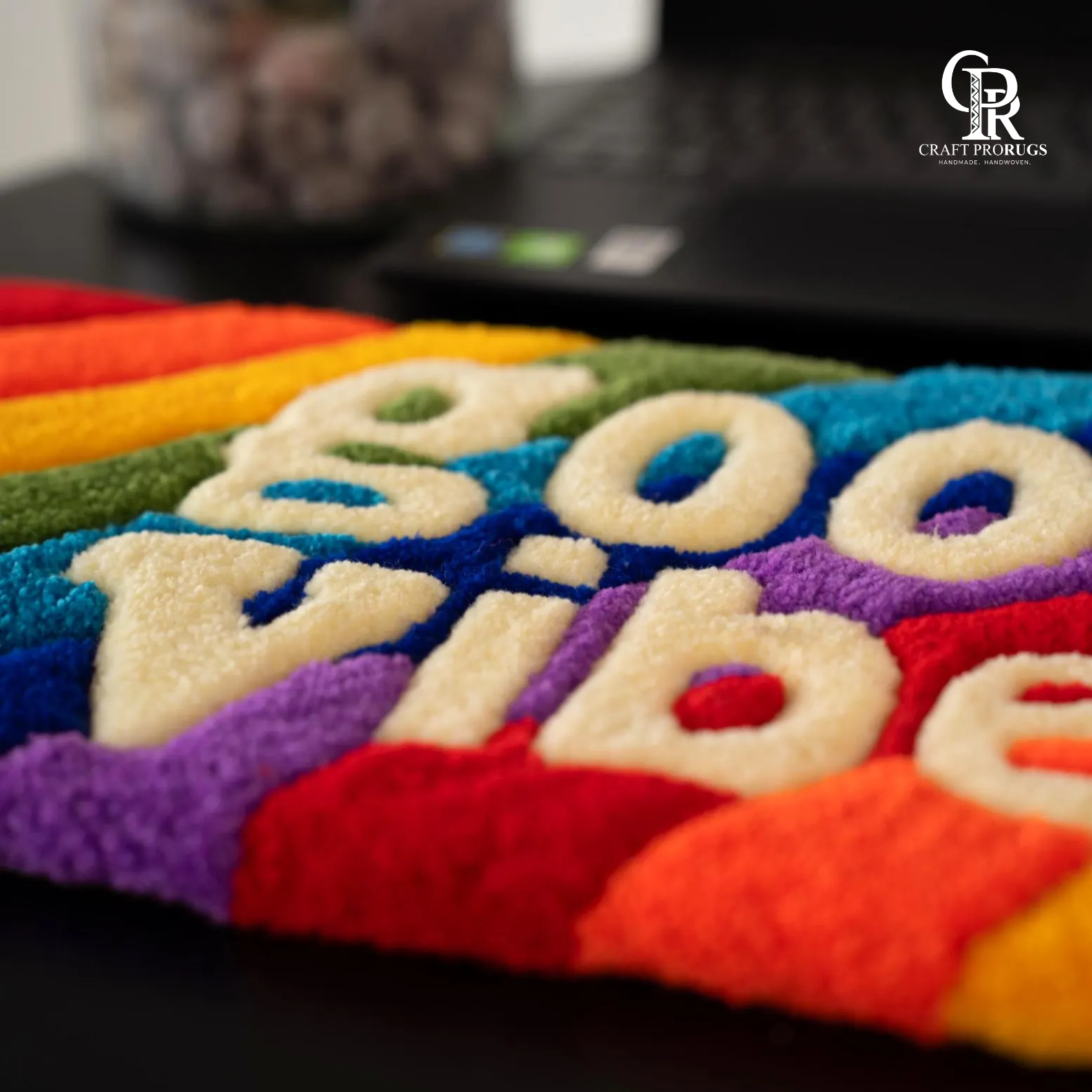 Diagonal view of Vibe Stripe Keyboard Rug placed under keyboard with rainbow color pattern and cozy wrist support”